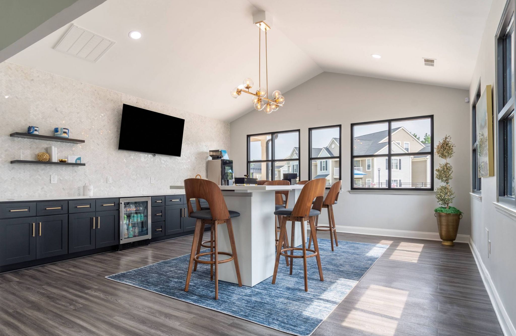 Hawthorne at the Pines modern clubhouse kitchen with dark cabinetry and bar seating, elegant pendant lighting, and a large window with a view.